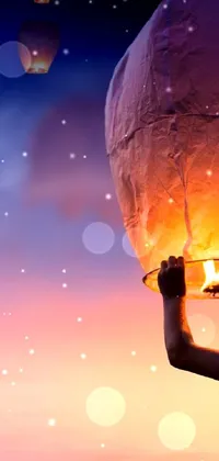 This conceptual phone live wallpaper features a man holding up a lantern towards the visually-stunning sky