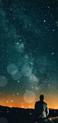 This phone live wallpaper depicts a mesmerizing night sky displaying a man fishing aboard a boat