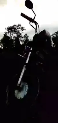 This stunning live phone wallpaper features a black and white photo of a motorcycle in the forest at twilight, complete with an Instagram filter for a unique touch