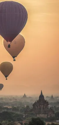 This live phone wallpaper showcases a beautiful cityscape with hot air balloons floating in the clouds