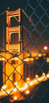 Looking for a stunning live wallpaper for your phone? Check out this amazing view of the Golden Gate Bridge through a chain link fence