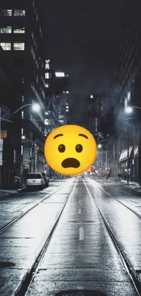 Looking for a fun and charming live wallpaper for your phone? Check out this quirky design featuring a yellow smiley face sitting on the side of a rainy city street