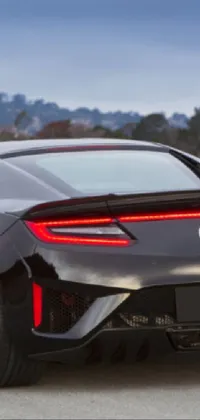 This phone live wallpaper showcases a black sports car driving down a winding road