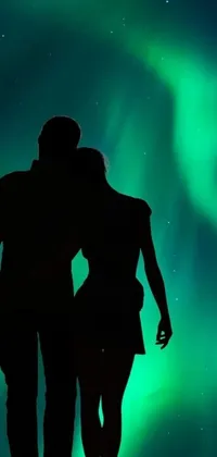This phone live wallpaper features a romantic scene with a man and woman standing against a stunning northern lights background