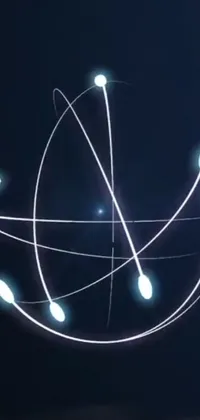 This phone live wallpaper showcases a close-up of a hand holding a mobile device with a kinetic art style, glowing halo, and orbiting spaceships against the backdrop of a Newton's cradle