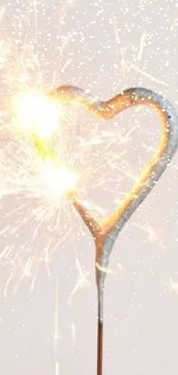 Looking for a magical and whimsical wallpaper for your phone? Look no further than this sparkling heart live wallpaper! With a close-up view of a heart-shaped sparkler, this wallpaper will add a delightful touch to your device's homescreen