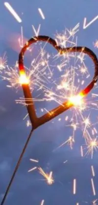 Enhance the look of your phone with this stunning live wallpaper featuring a heart-shaped sparkler on a soft-focused background