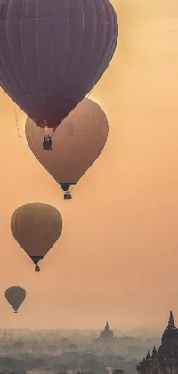 This phone live wallpaper displays a mesmerizing scene of numerous hot air balloons soaring over a city with a beige mist in the background