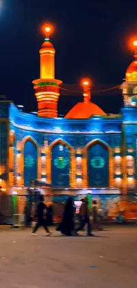 Discover a stunning live wallpaper of a group of people in front of a majestic building, surrounded by beautiful mosques and orange street lights