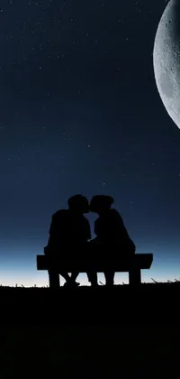 This stunning live wallpaper for your phone depicts a fantasy image of two individuals sitting on a bench gazing up at the full moon
