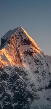 This live wallpaper for phones portrays a stunning mountain adorned in snow with a blue sky overhead