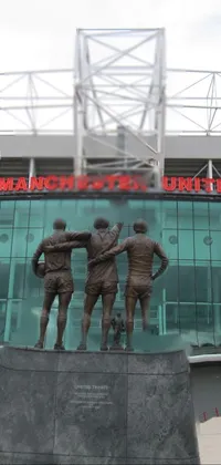 This phone live wallpaper features a captivating statue of three soccer players set against a grand stadium