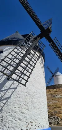 This phone live wallpaper features a serene image of a white and blue windmill on top of a hill