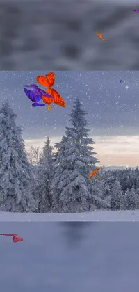 This phone wallpaper features lively kites soaring in the sky against a scenic backdrop of a snow-covered forest