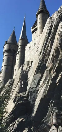 Decorate your phone's background with a live wallpaper showcasing a castle built into a mountainside, reminiscent of the famous Hogwarts