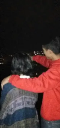 This phone live wallpaper showcases a stunning night vista from atop a hill, with a couple in a romantic embrace