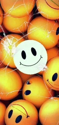 This mobile wallpaper showcases a white smiley face grinning lasciviously as it pops out of a vibrant pile of oranges