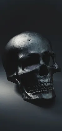 This dark live phone wallpaper features a close-up view of a highly detailed bronze skull on a black background