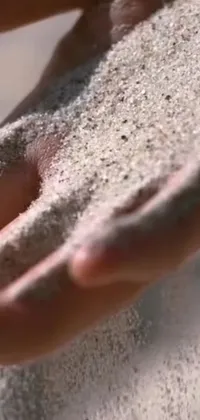 This phone live wallpaper showcases a mesmerizing close-up of hands holding sand in dynamic kinetic pointillism style