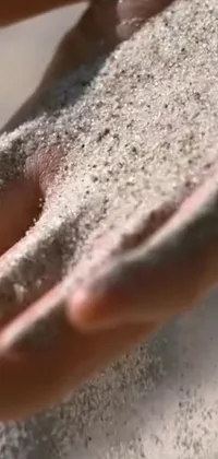 Enjoy the beauty and tranquility of nature with this phone live wallpaper featuring a close up of hands holding sand