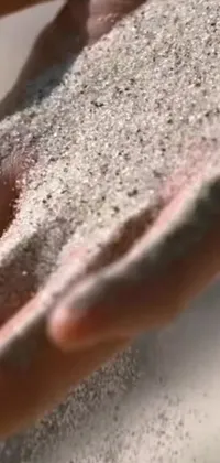 This phone live wallpaper showcases a mesmerizing scene of a hand holding sand using kinetic pointillism techniques