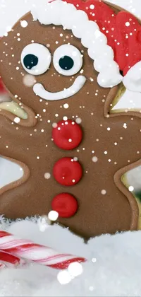 This live wallpaper depicts a gingerbread cookie on a snowy background surrounded by candy canes, a picture, and frosting accents