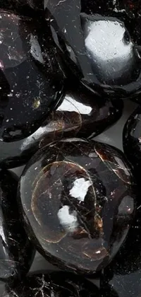 Get mesmerized by this phone live wallpaper featuring a striking pile of black rocks on a white surface