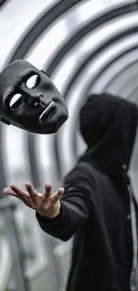 This captivating phone live wallpaper features an enigmatic figure throwing a black fabric mask into the air