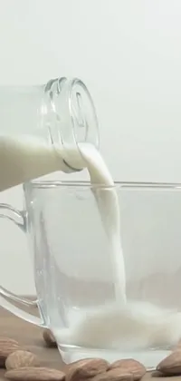 This phone live wallpaper features a close-up view of a glass of almond milk being poured into a cup