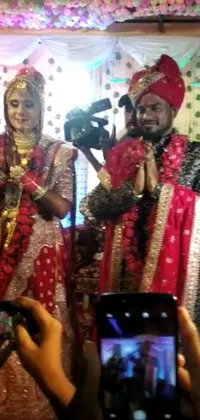 Phone live wallpaper featuring a group of people capturing pictures of a lovely couple dressed in a beautifully detailed jodhpuri suit