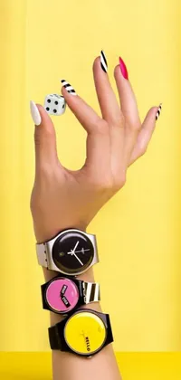 This live phone wallpaper features a close-up of a wristwatch-wearing hand with bold, geometric designs inspired by popular art styles and brands