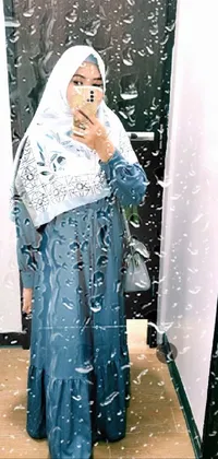 Get inspired with this live wallpaper for your phone featuring a woman donning a stylish blue-grey multilayered outfit while taking a mirror selfie