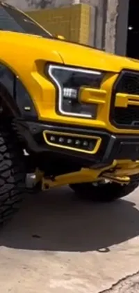 This phone live wallpaper features a vibrant yellow Ford F-150 Raptor parked in front of a building