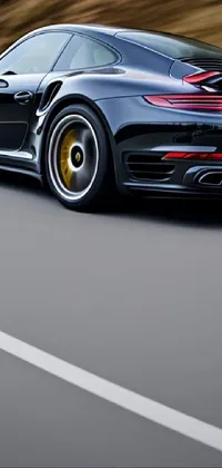This stunning black Porsche sports car live wallpaper features a close-up profile view of the vehicle as it speeds down a winding road
