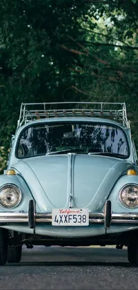 Bring a chic and vintage vibe to your phone screen with a blue VW beetle parked on a picturesque road