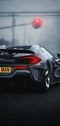 This phone live wallpaper showcases a sports car racing down a road, featuring a close-up of a McLaren with back lights illuminating the scene