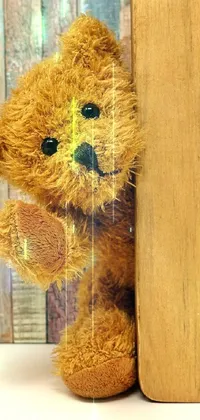 This mobile wallpaper features a delightful brown teddy bear situated beside an open book set against wooden paneling