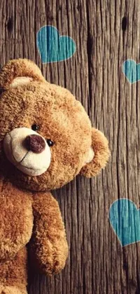 Looking for an adorable and charming phone wallpaper? Check out this live wallpaper that features a cute teddy bear leaning against a rustic wooden wall