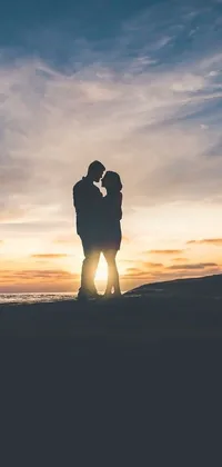 This live phone wallpaper features a stunning image of a couple sharing a romantic kiss on a sunset beach