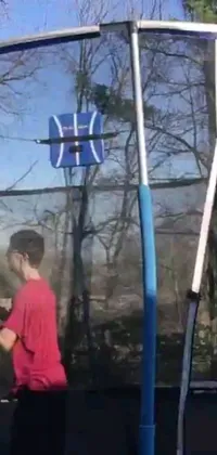 This live wallpaper showcases a young boy playing tennis on a trampoline in his backyard