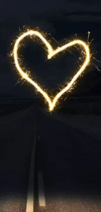 This live wallpaper features a heart-shaped sparkler at the center of a dark desert highway