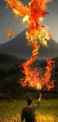 This Phone Live Wallpaper features a striking digital artwork of a man standing on a green field, casting a fire spell through the orange-colored fire