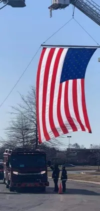 This phone live wallpaper features a vivid American flag waving on a firetruck with a picture frame in the background