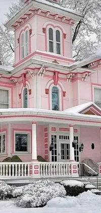 This stunning phone live wallpaper showcases a snow-covered pink house nestled beside a tree