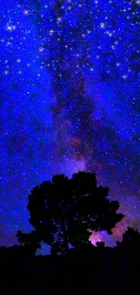 This phone live wallpaper features a breathtaking night sky with a striking tree in the foreground