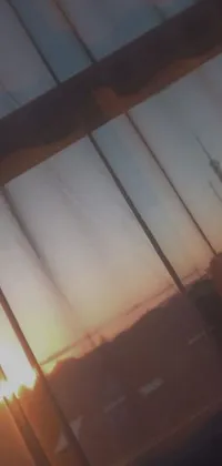 Bring tranquility to your phone with this gorgeous live wallpaper featuring a window, sunset, and skyline in the background