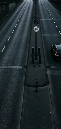This stunning live wallpaper features an image of a car parked on the side of a road in a dark cityscape