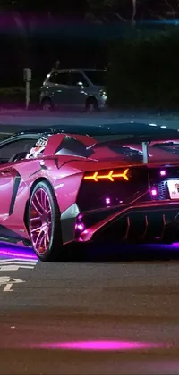 This live wallpaper features a striking pink sports car parked on a neon-lit road in Tokyo, reminiscent of the Lamborghini Veneno