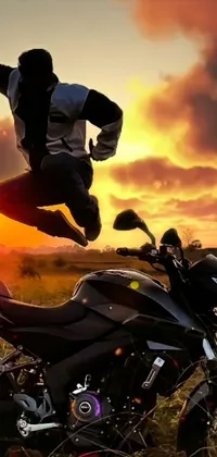 This phone live wallpaper depicts a man jumping in the air next to a motorcycle against a sunset backdrop