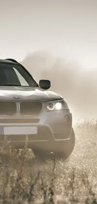 Looking for a mesmerizing live wallpaper for your phone? Check out this stunning BMW SUV parked in a field on a foggy day